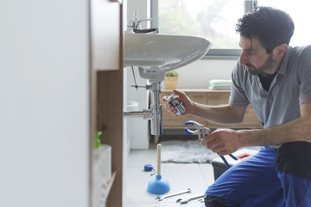 Plumber repairing sink with tools, highlighting spring plumbing maintenance and proactive service by Plumbing Today HVAC Omaha.